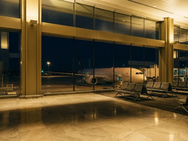 Airport boarding gate at night with a widebody aircraft beyond the glass