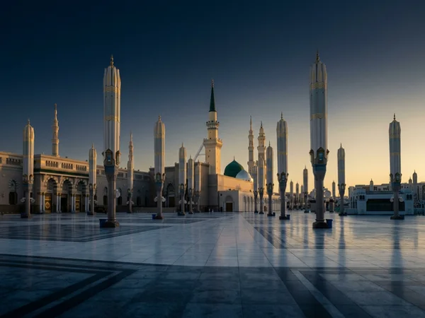 Marble plaza outside the Prophet's Mosque with shade umbrellas at dawn